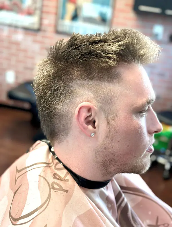 Side view of a mid fade with a spiked, textured blonde top